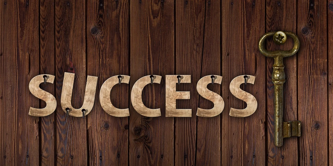 Wooden letters spelling success with key on wall.