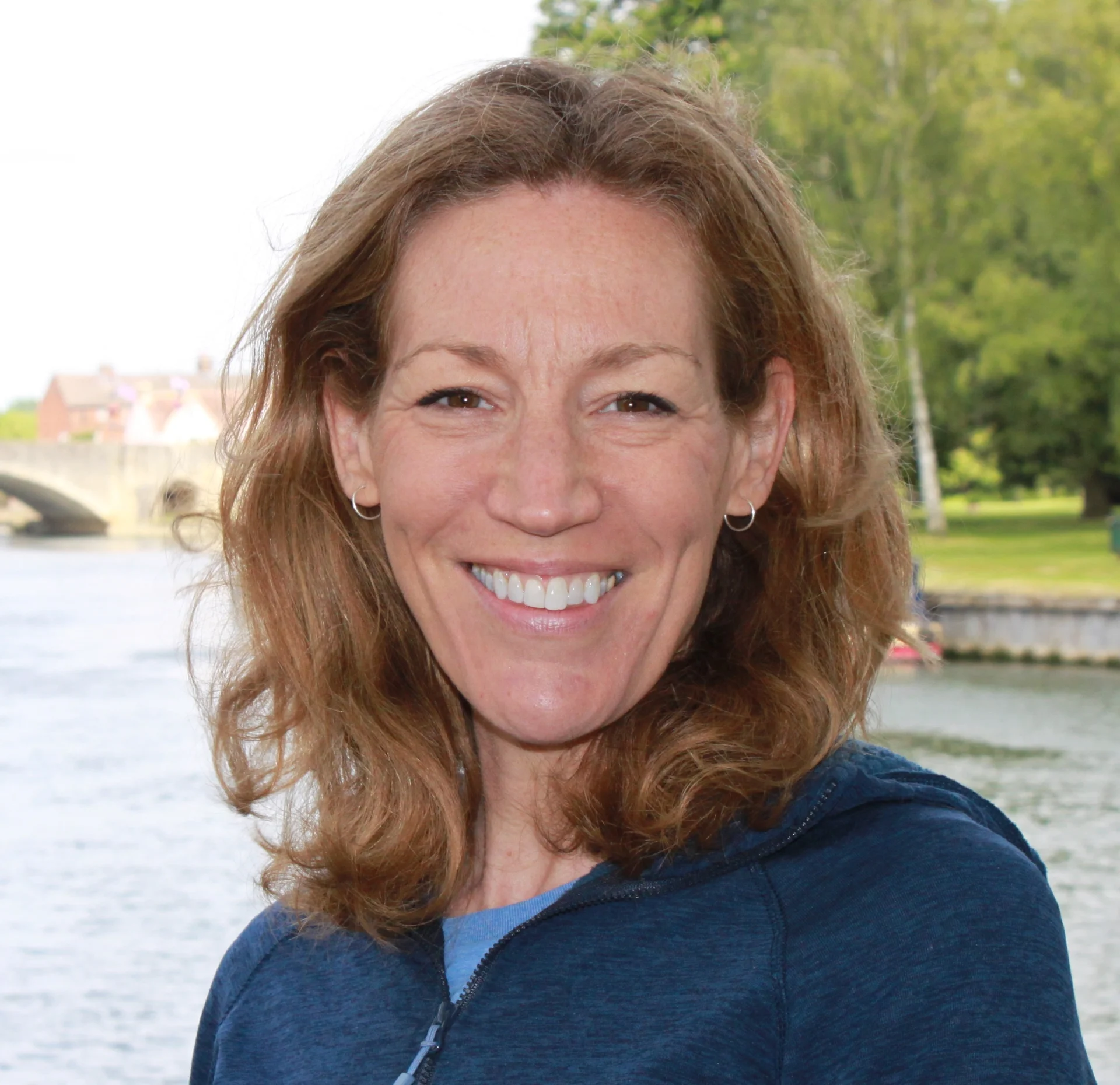 Smiling person outdoors by a river.